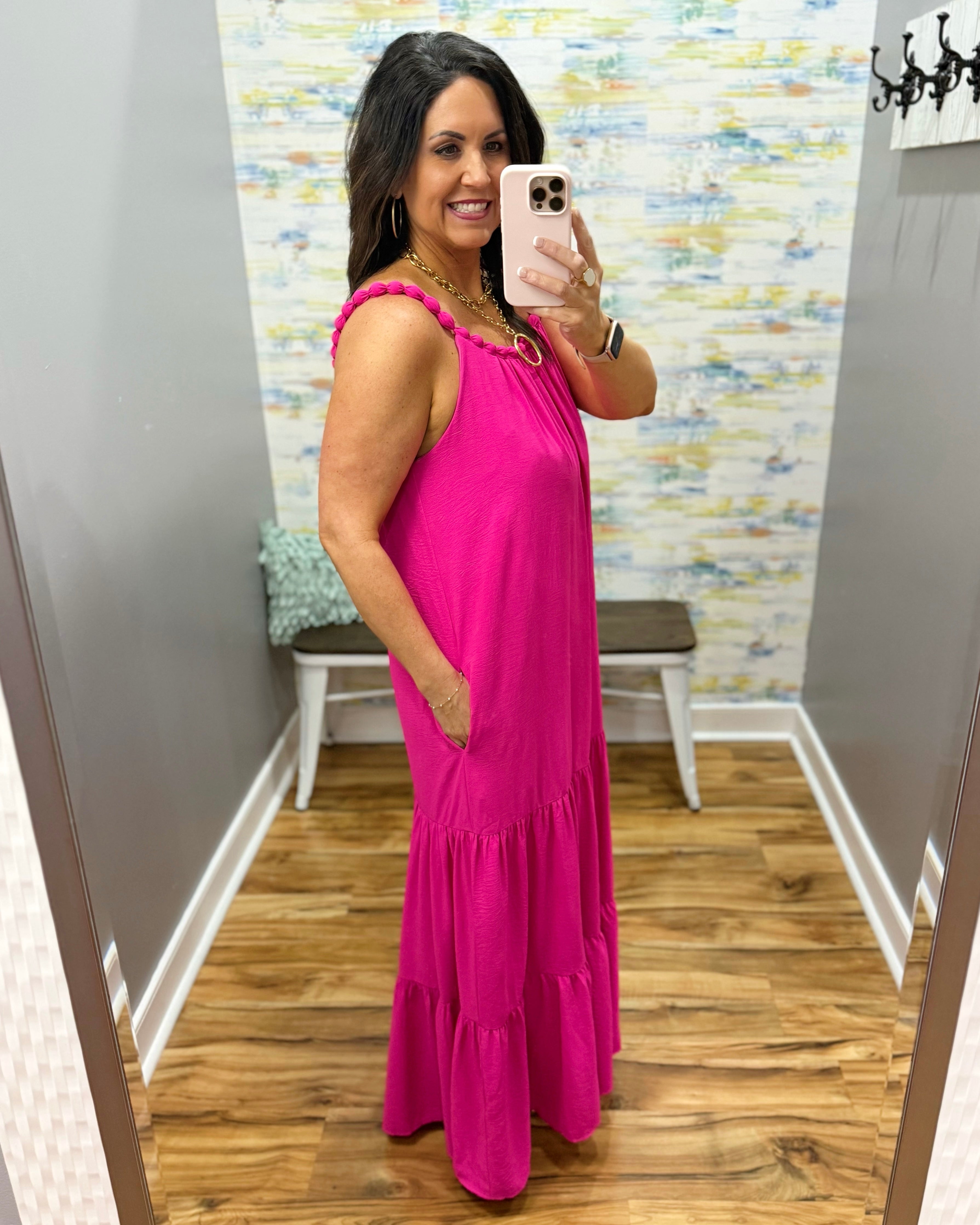 Woman in a pink dress taking a mirror selfie in a room with a colorful wall.