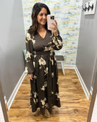 A woman takes a mirror selfie in a fitting room wearing a dark brown long-sleeve maxi dress with a beige floral pattern and a matching waist tie belt.