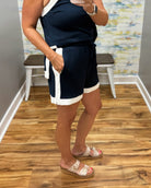 Person wearing a navy and white outfit with shorts and a top, standing on a wooden floor.