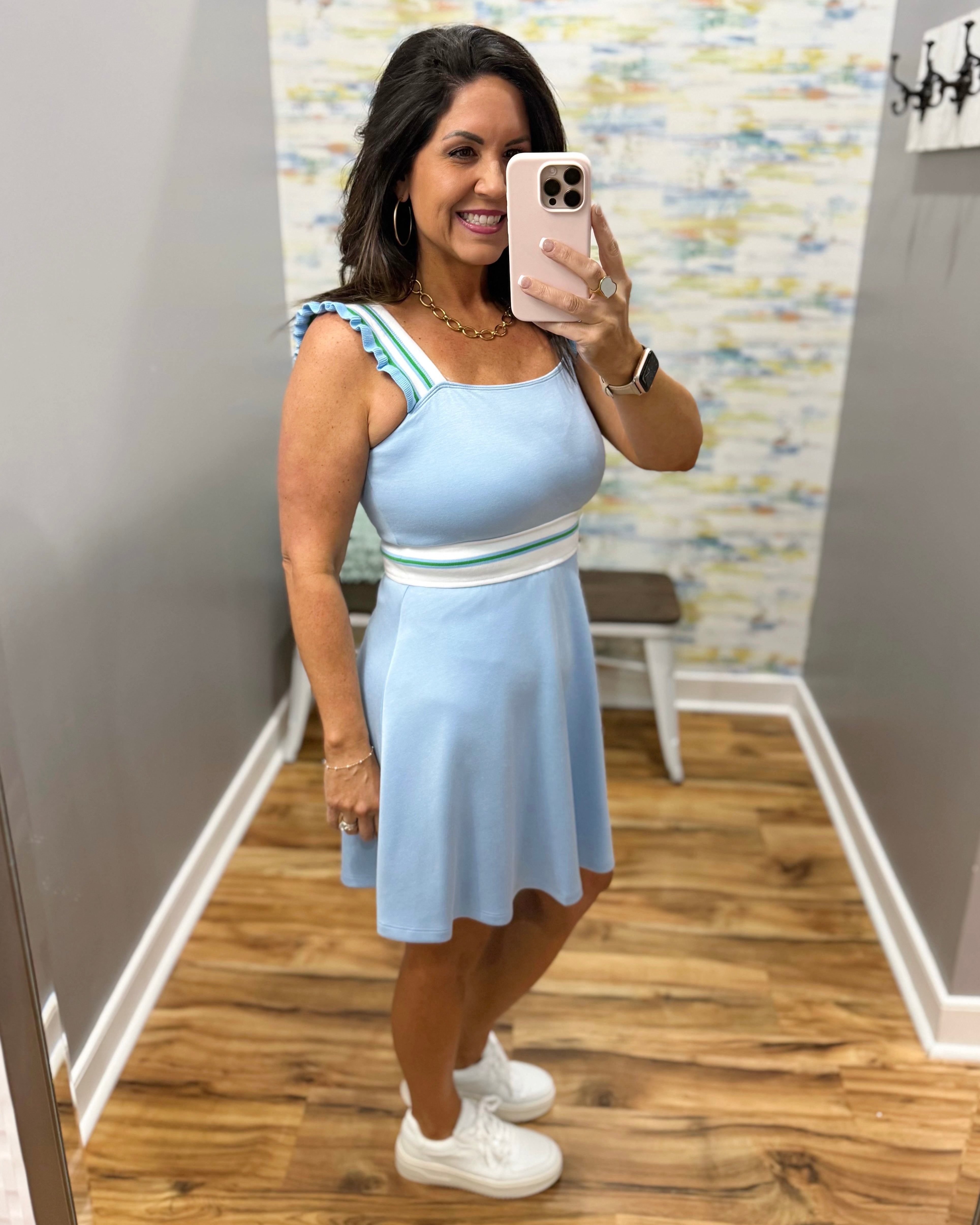 Woman taking a mirror selfie wearing a light blue dress with a striped top.