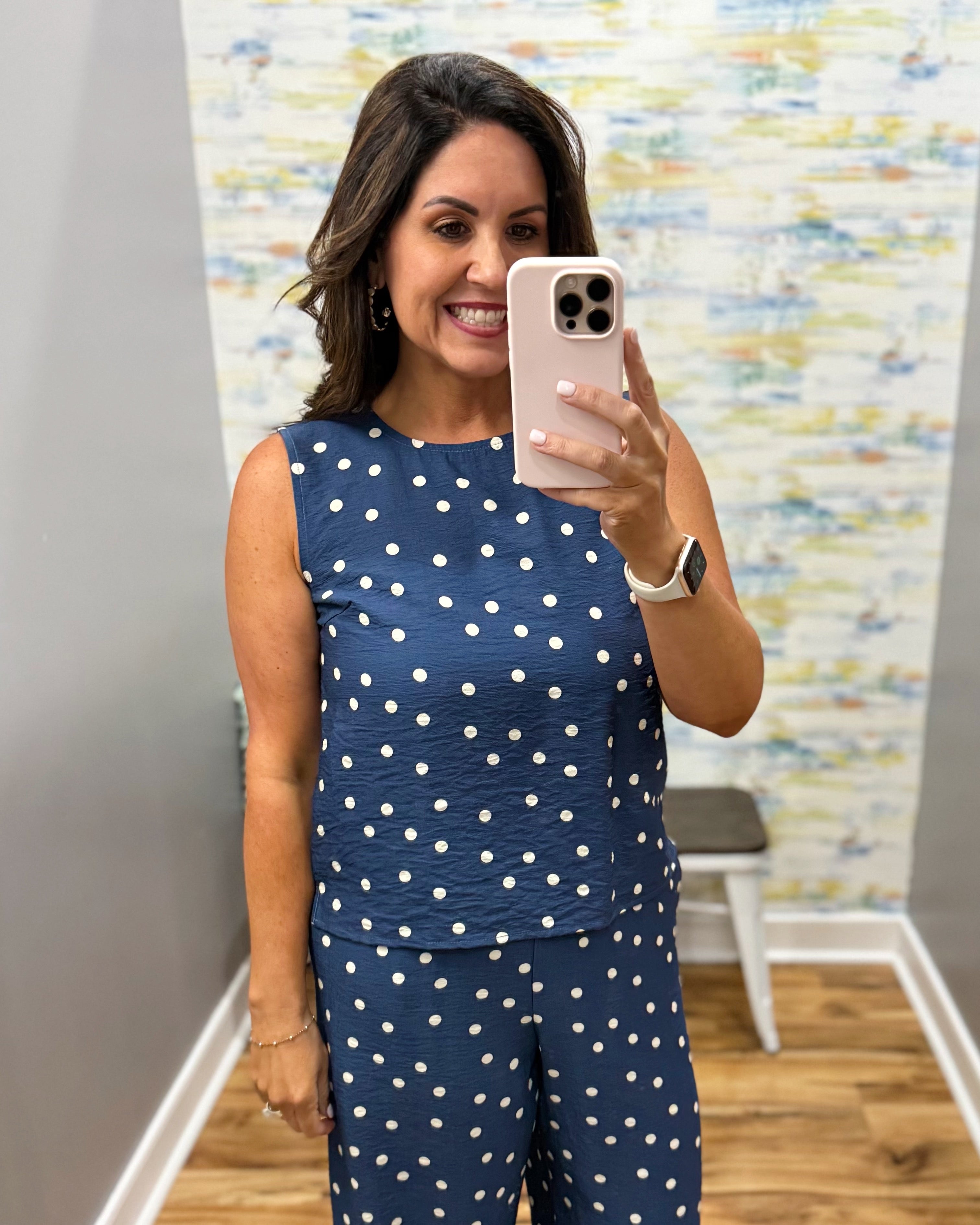 Woman taking a mirror selfie wearing a navy blue polka dot outfit.