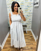 Woman wearing a white dress in a room with a patterned wall.