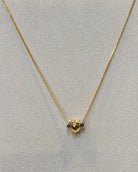 This dainty snake chain necklace features a slim polished chain with two small rounded bead sliders that sit together at the center in two tone finish.