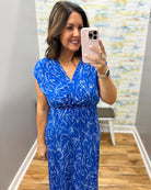 Woman taking a mirror selfie wearing a blue dress with a white pattern.