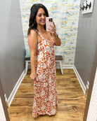 Woman taking a mirror selfie wearing a patterned dress in a room with a colorful wall.