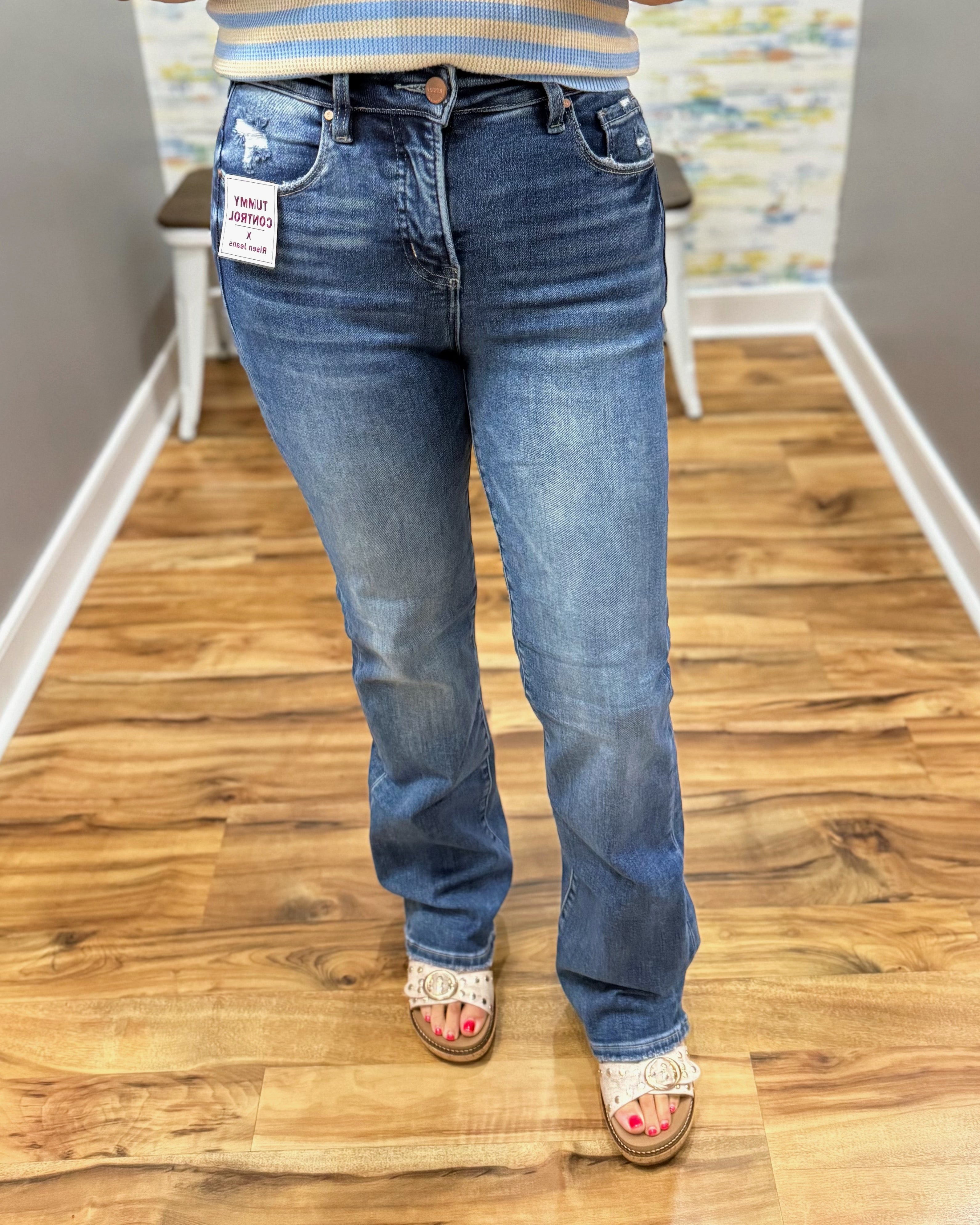 Person wearing blue jeans standing on a wooden floor with a colorful wall in the background