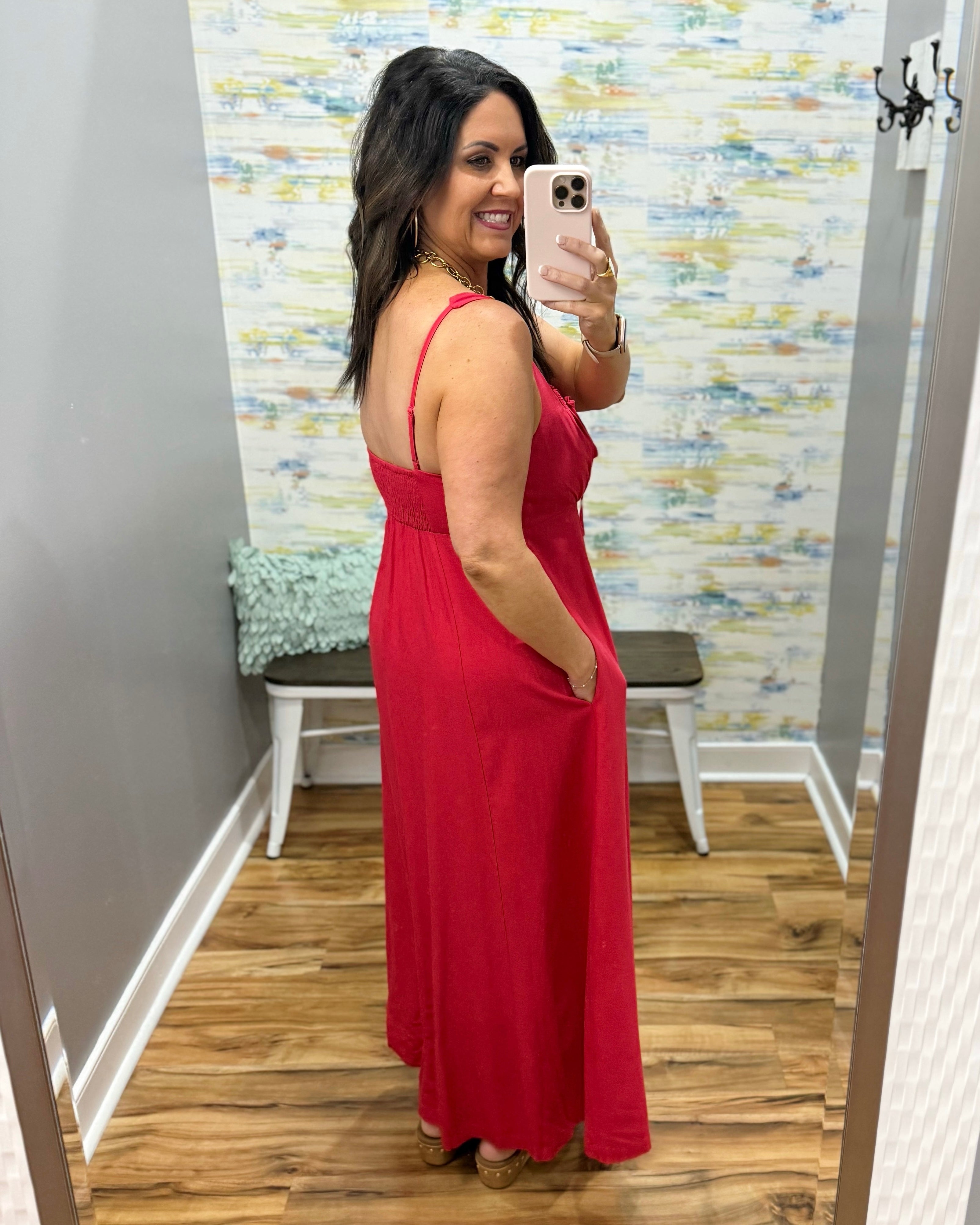 Woman in a red dress in a room with a patterned wall.