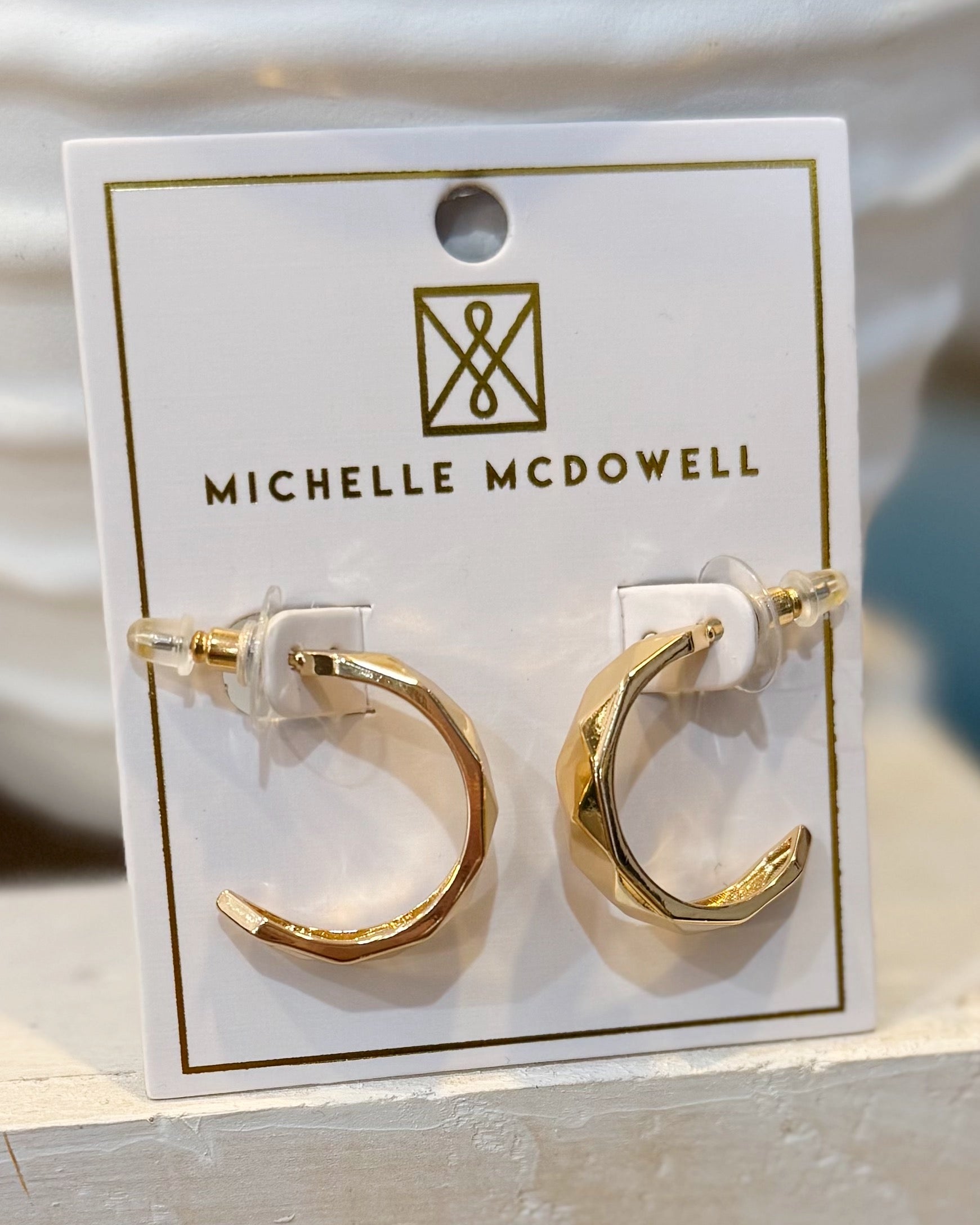 Gold hoop earrings on a Michelle McDowell branded card.