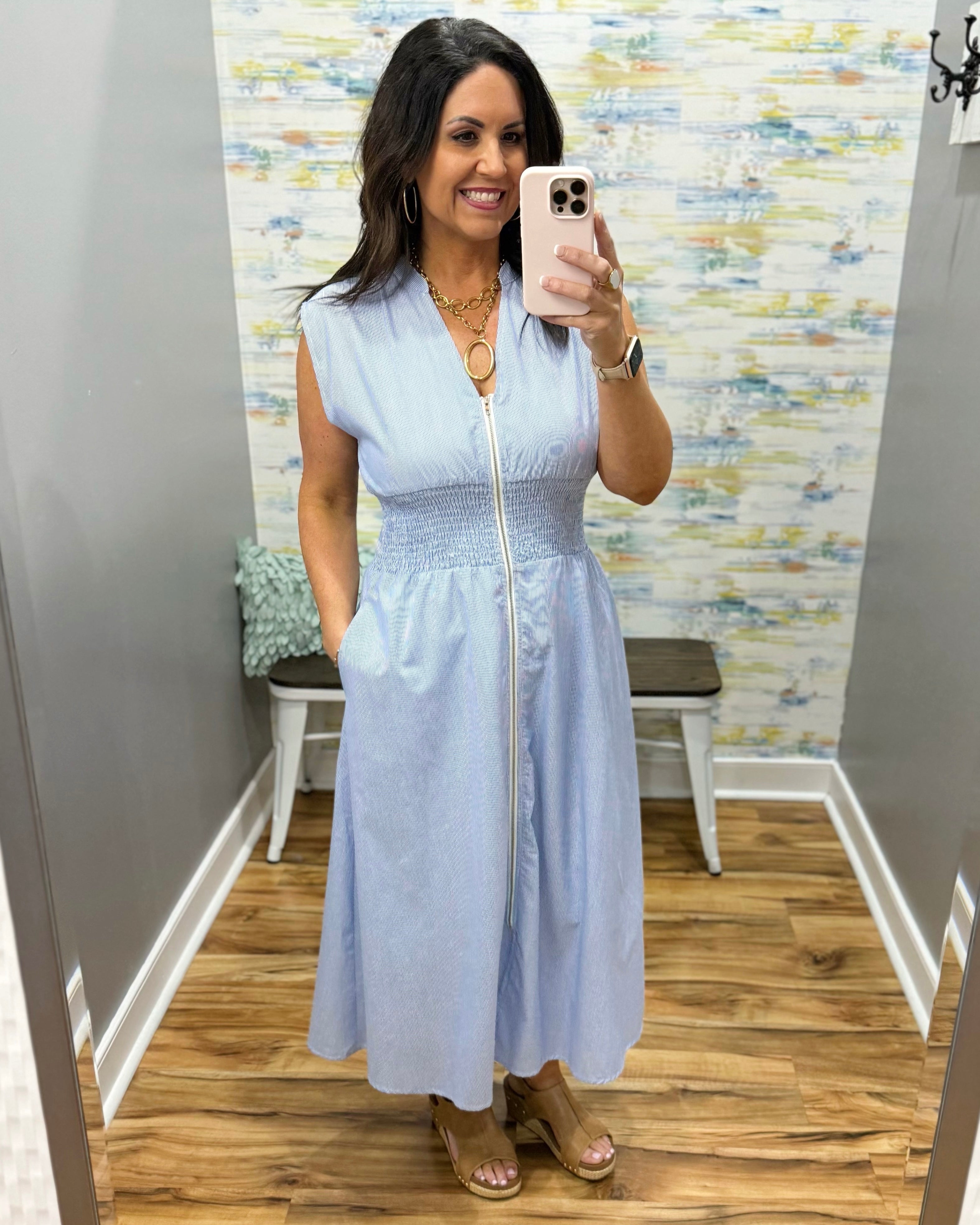 Woman wearing a light blue dress in a room with a patterned wall.
