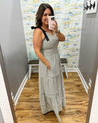 Woman taking a mirror selfie wearing a striped dress in a room with a colorful wall.