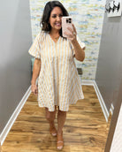 Woman taking a mirror selfie wearing a natural and white striped dress.