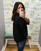 woman wearing a black 3/4 sleeve flowy top.