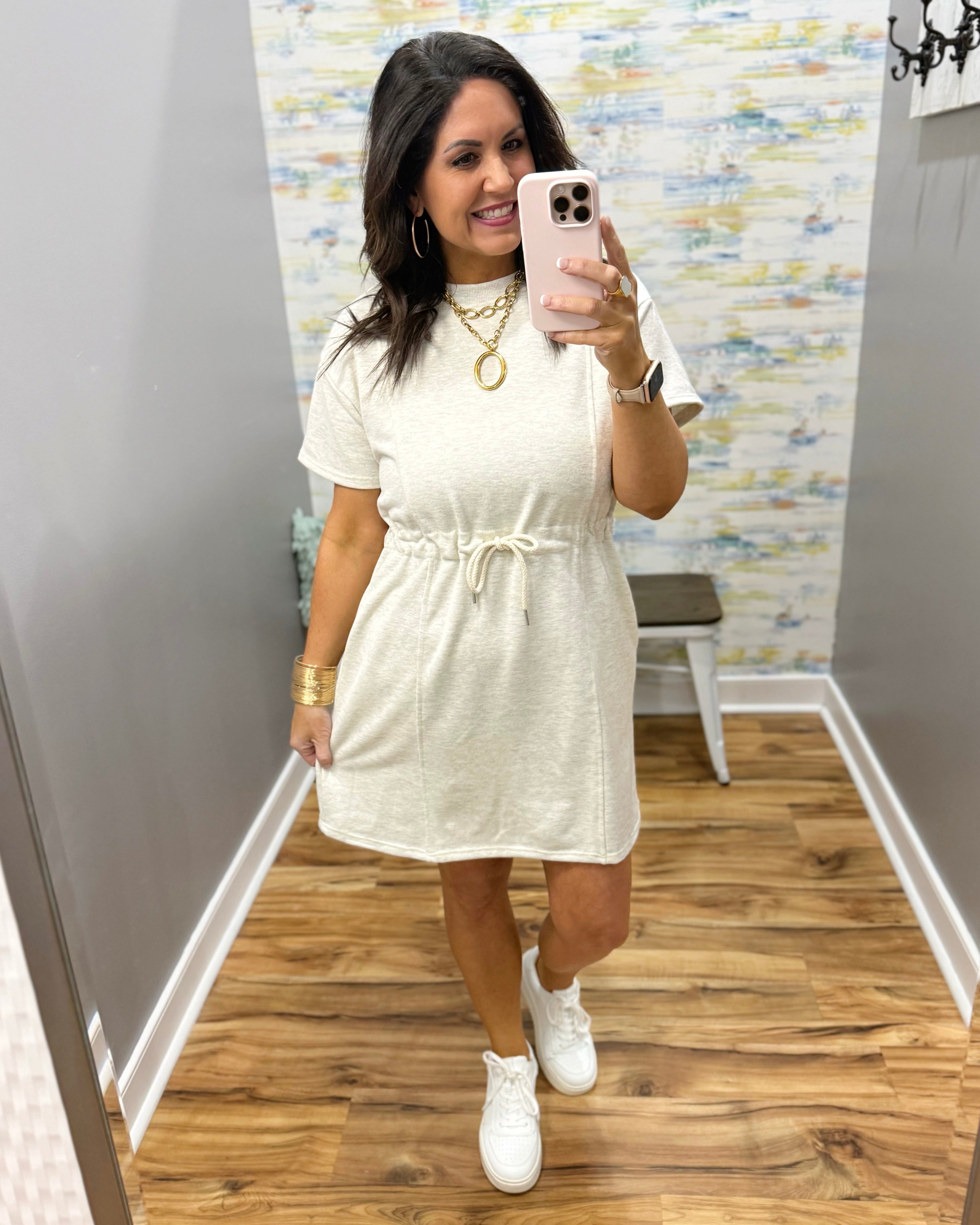 Woman wearing a neutral dress and white sneakers.