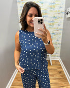 Woman taking a mirror selfie wearing a navy blue polka dot outfit.