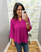 woman wearing a magenta color 3/4 sleeve flowy top.