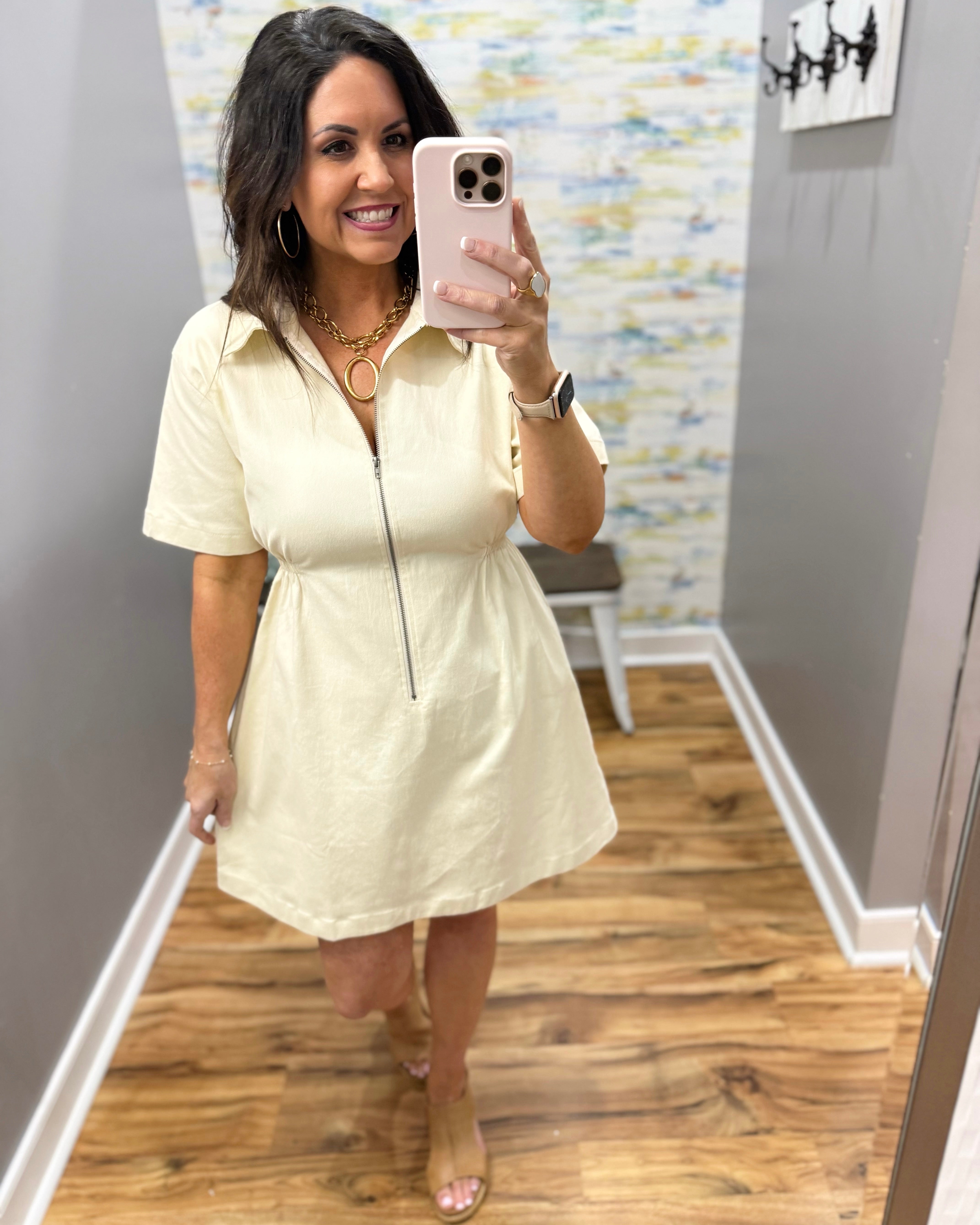Woman wearing a light-colored dress in a room with a textured wall.
