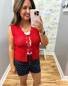 Woman taking a mirror selfie wearing a red sleeveless top and navy shorts with white polka dots.