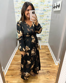 woman wearing a black maxi dress with brown and taupe floral pattern. 