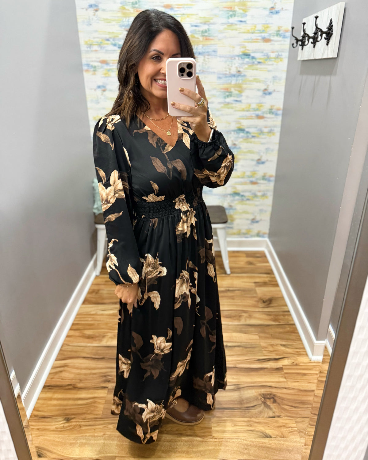 woman wearing a black maxi dress with brown and taupe floral pattern. 