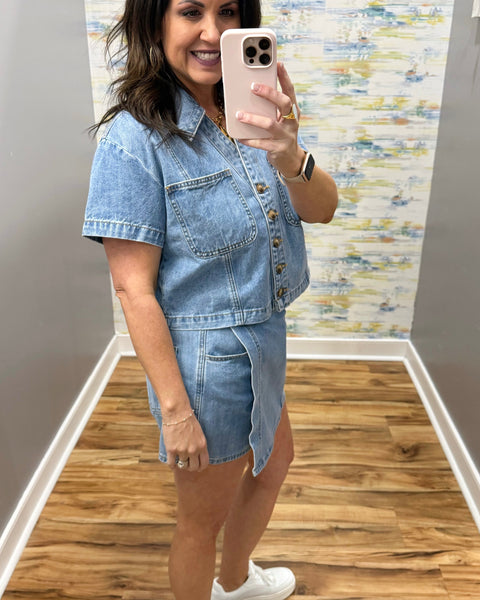 Woman wearing a denim skort and denim top with beige boots.