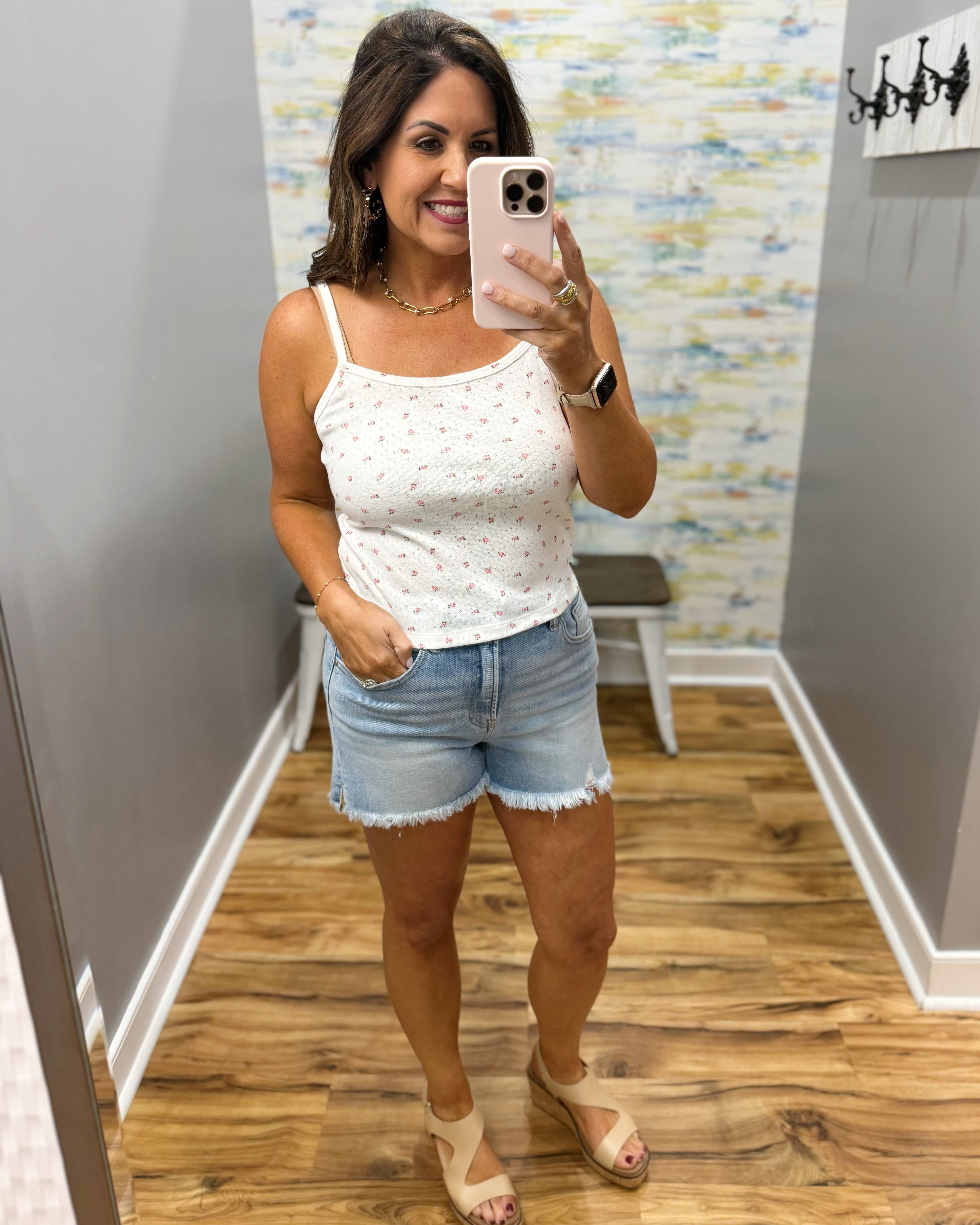 woman wearing white floral cami top with denim shorts.
