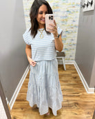Woman wearing a striped outfit in a room with a patterned wall.