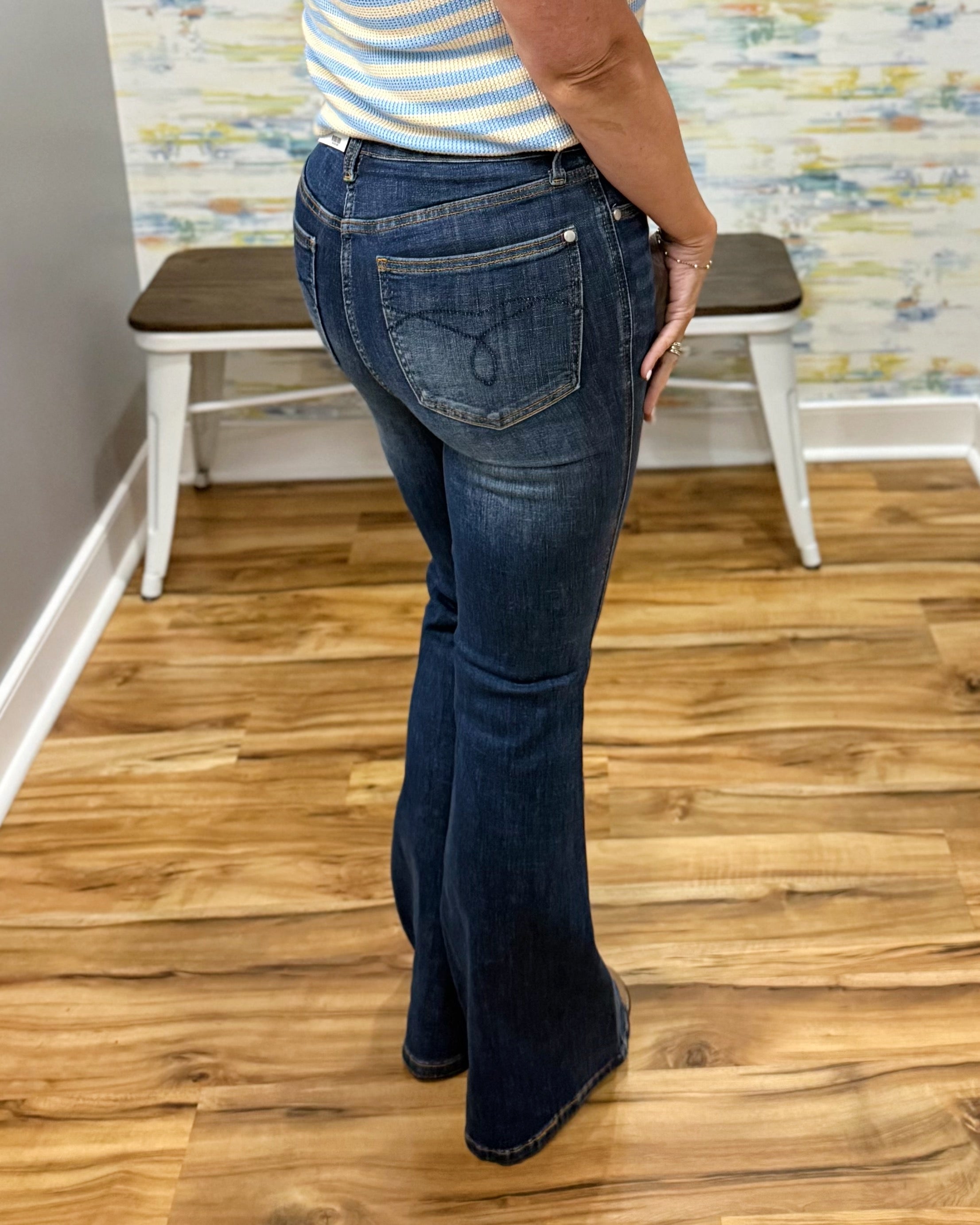 Person wearing blue jeans standing on a wooden floor with a colorful wall in the background