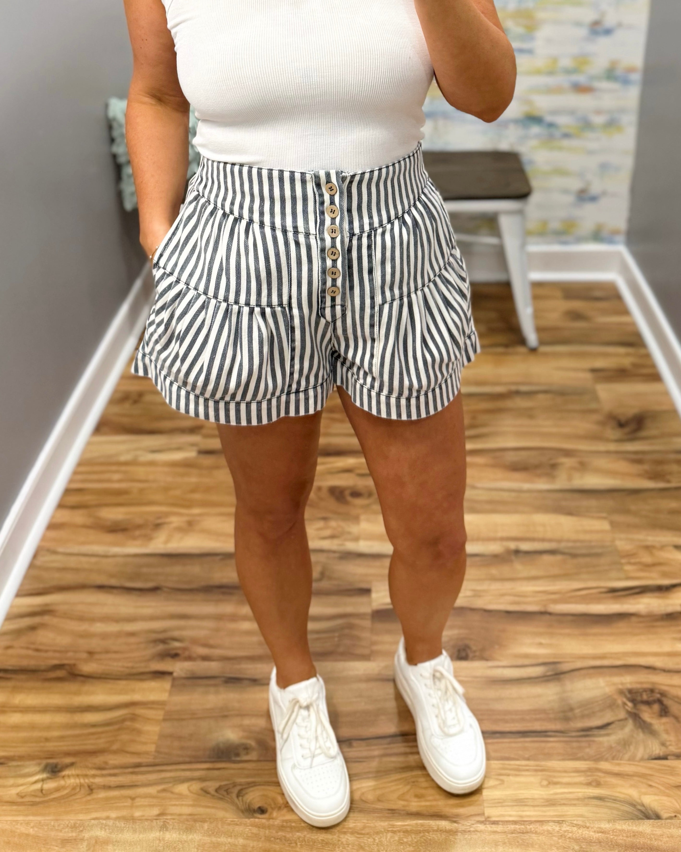 Person wearing a white top and black and white striped shorts on a wooden floor.