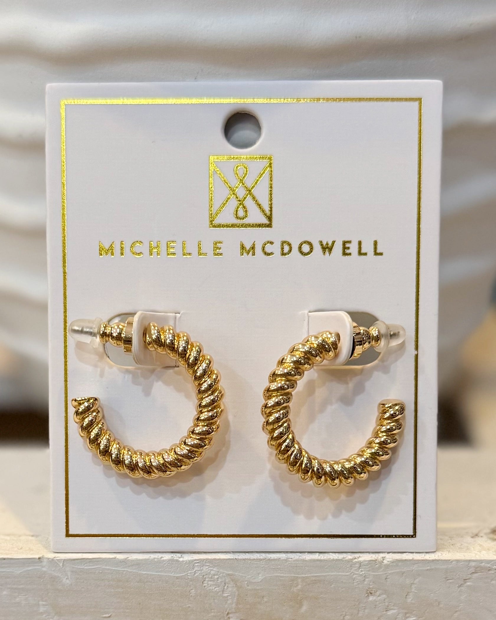 Gold hoop earrings on a Michelle McDowell branded card.