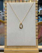 This organic oval open ring pendant necklace features a sculpted elongated oval ring with a molten wavy edge hanging from a fine gold tone chain.