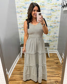 Woman taking a mirror selfie wearing a striped dress in a room with a patterned wall.