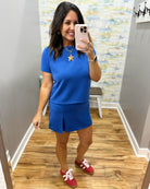 Woman taking a mirror selfie wearing a blue outfit with red sneakers in a room.