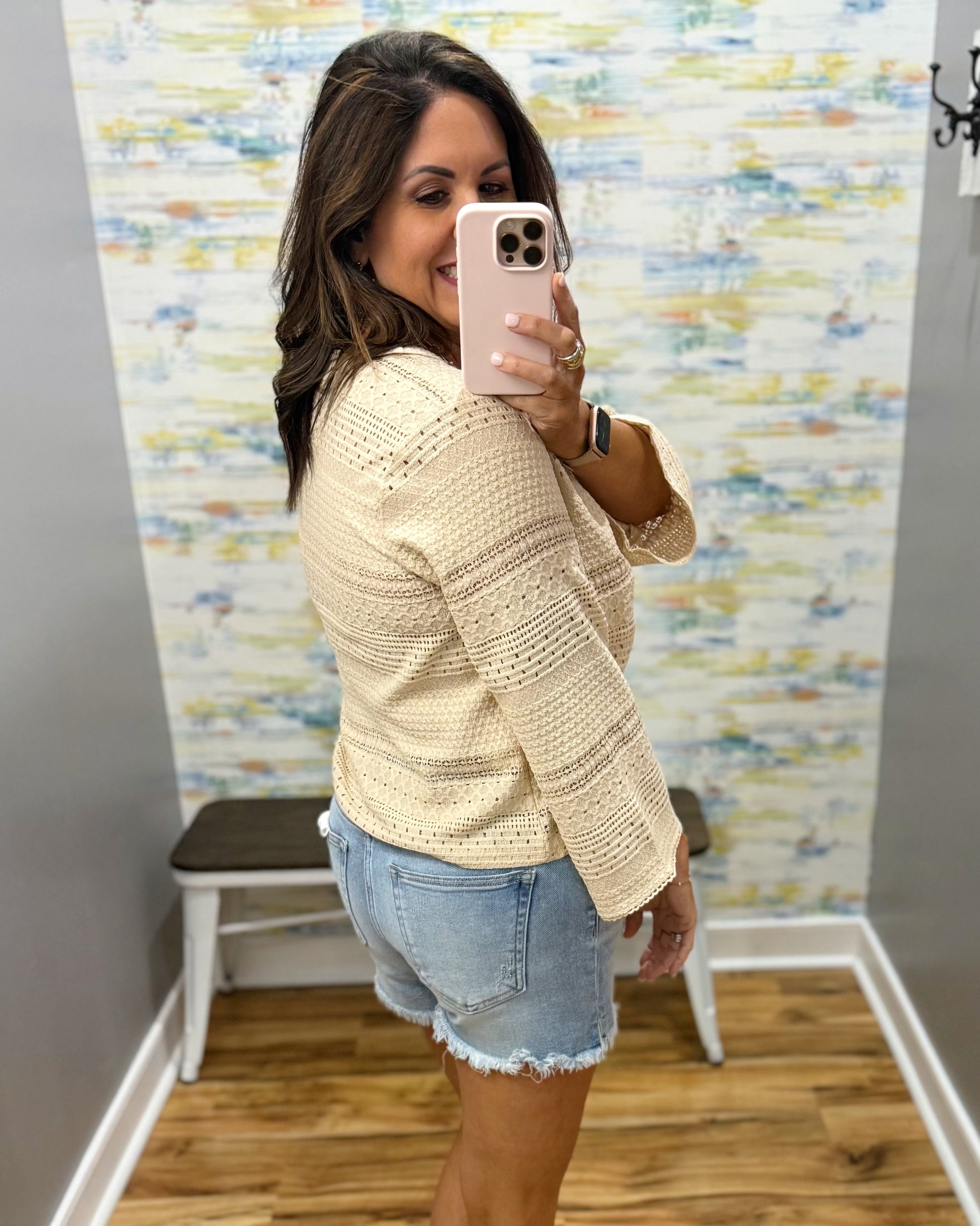 woman wearing a bell sleeve top in natural. 