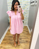 Woman taking a mirror selfie wearing a pink and white striped dress.
