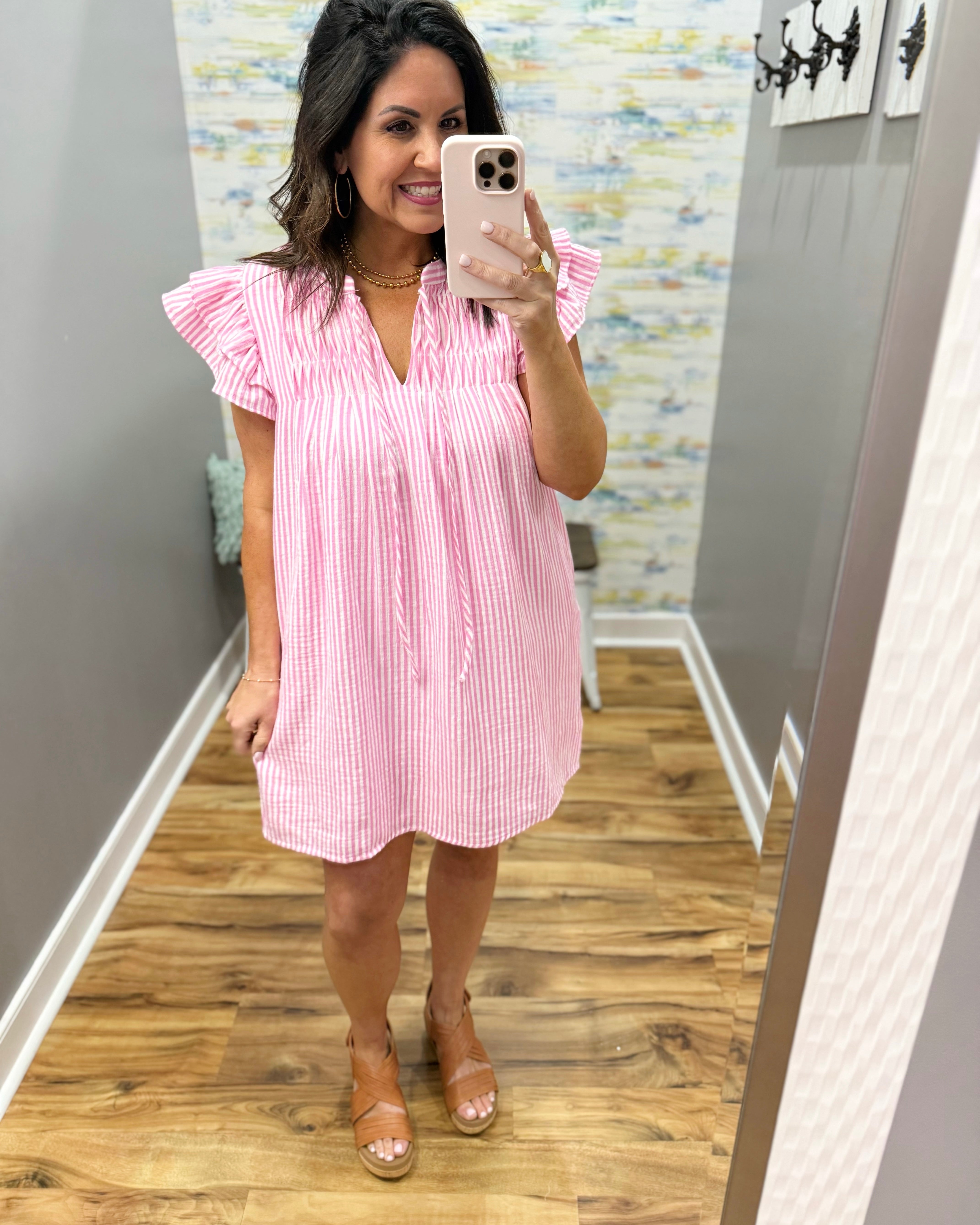 Woman taking a mirror selfie wearing a pink and white striped dress.