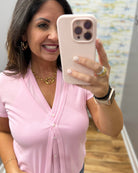 Woman in a pink shirt taking a selfie with a phone.