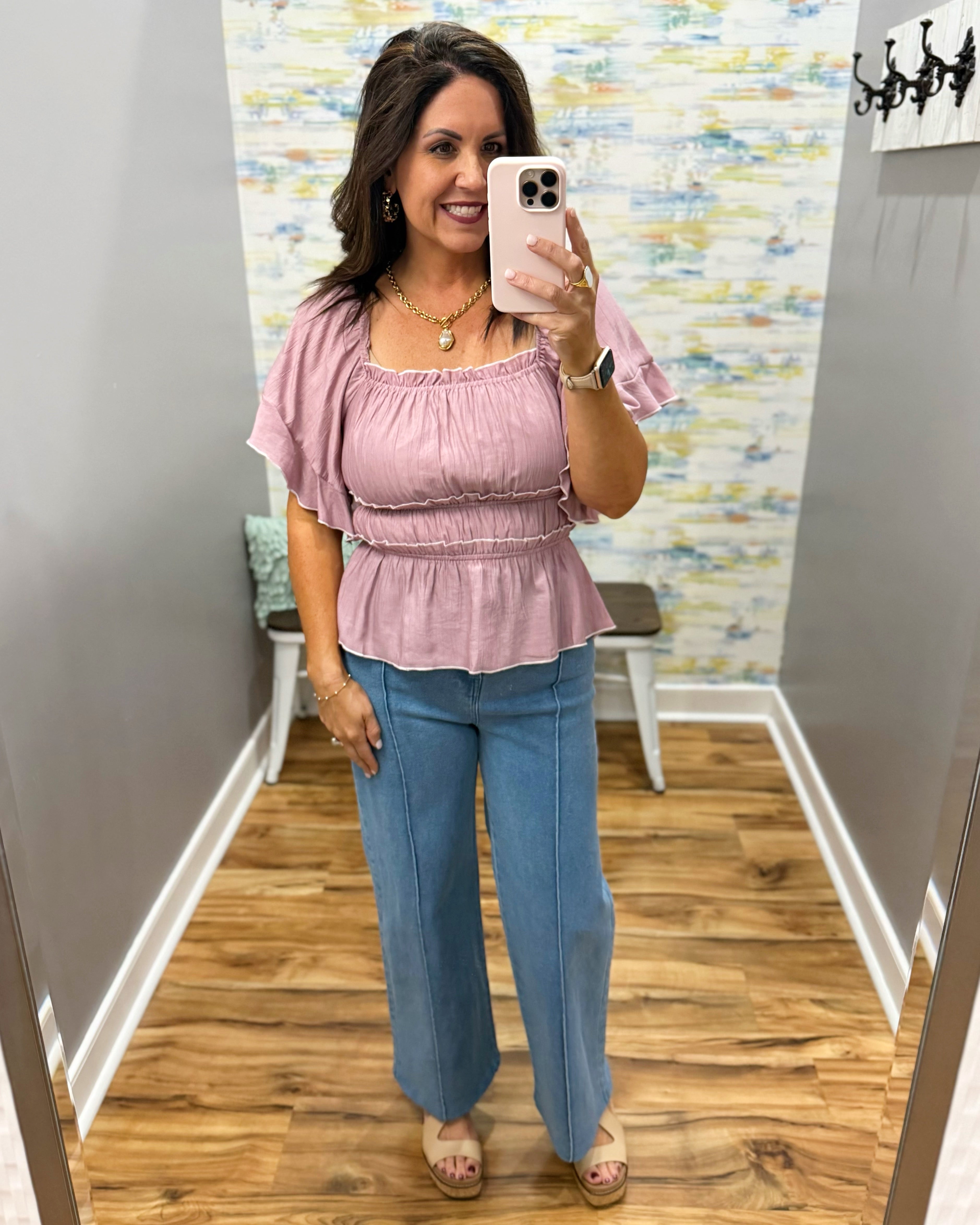 woman wearing wide leg denim pants and a mauve square neck top.