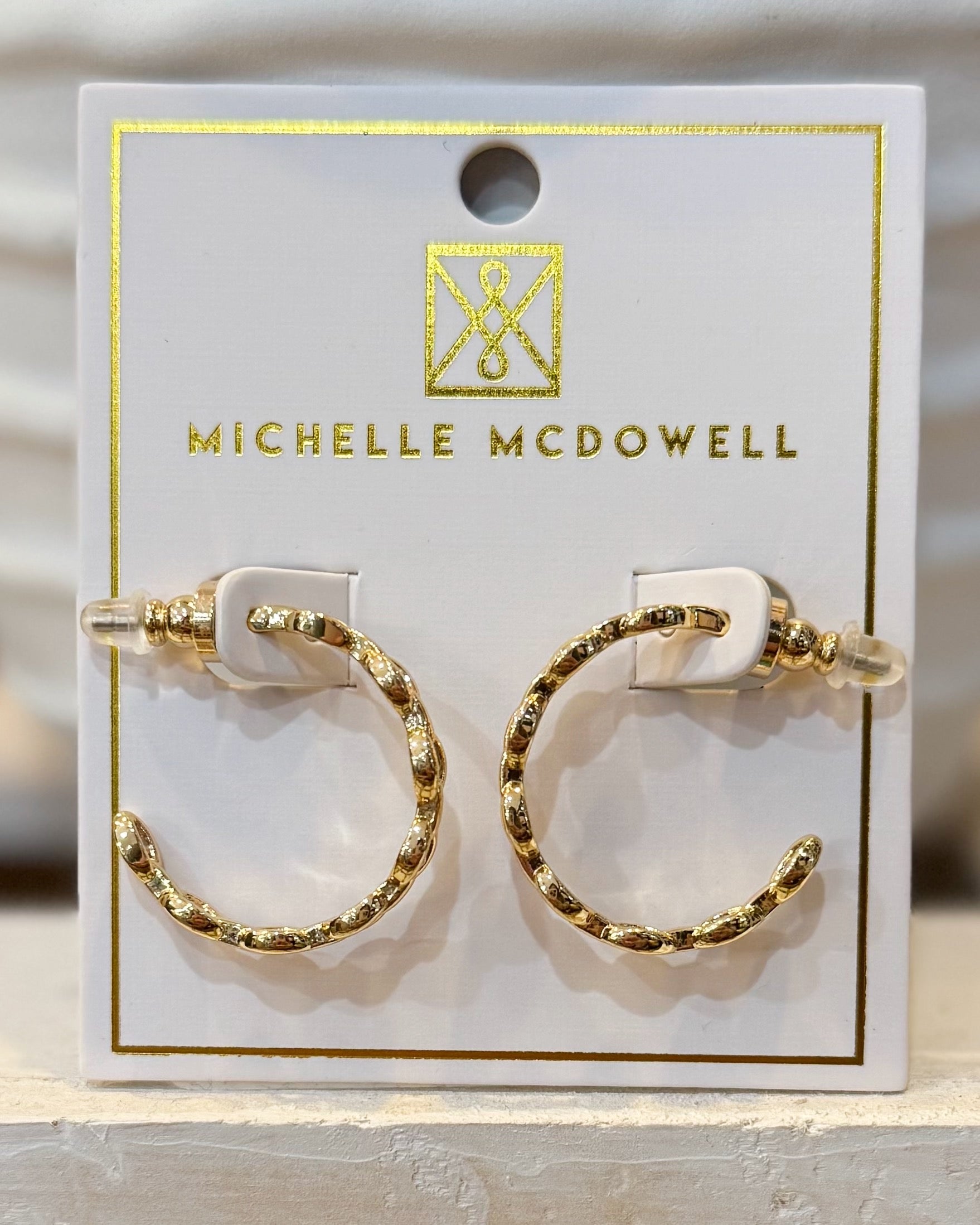 Gold hoop earrings on a branded card with 'Michelle McDowell' logo.