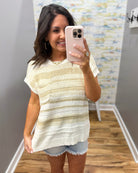 Woman taking a mirror selfie wearing a striped shirt and denim shorts in a room with a colorful wall.