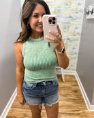 woman wearing dark green tank with denim shorts.