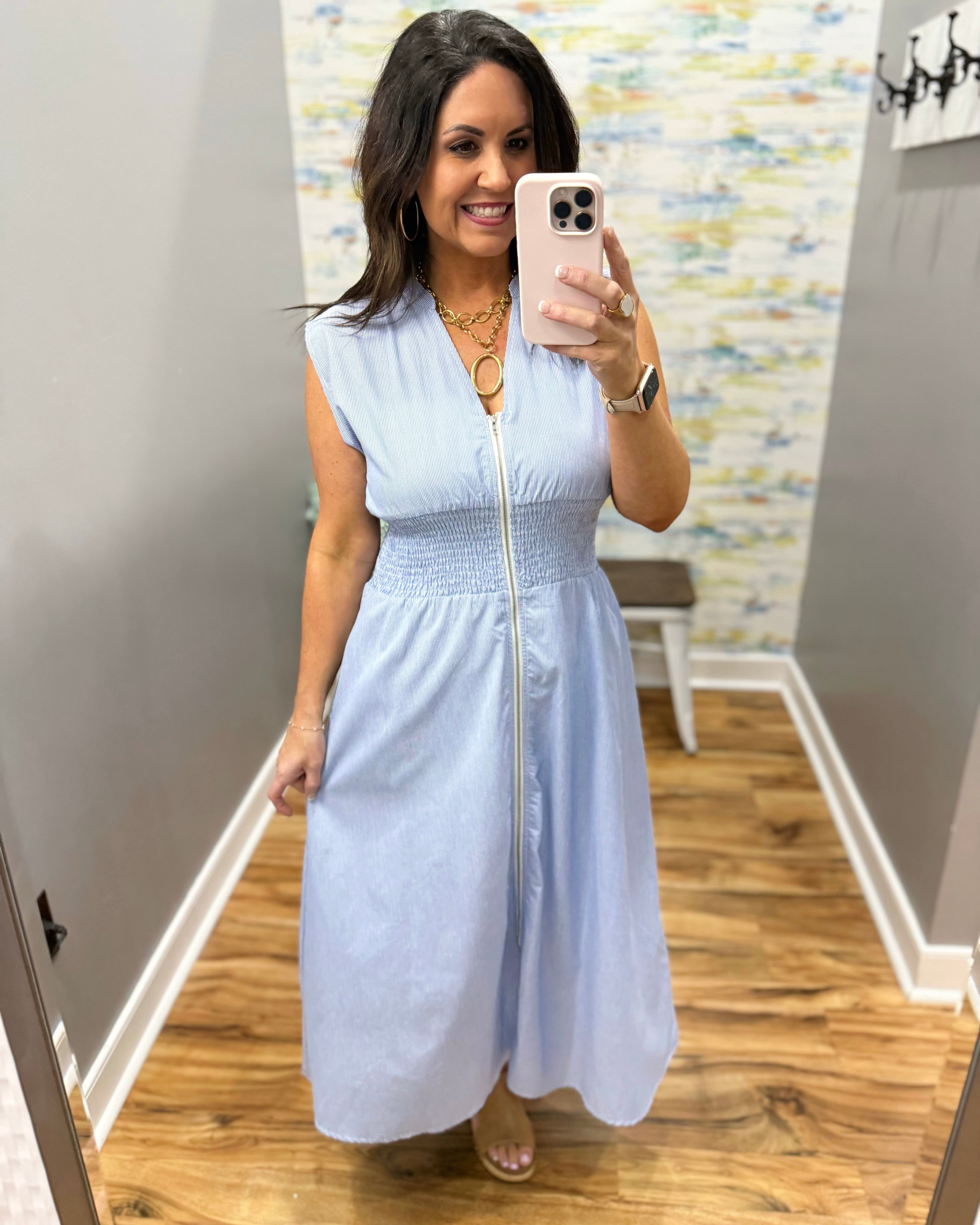 Woman wearing a light blue dress in a room with a patterned wall.
