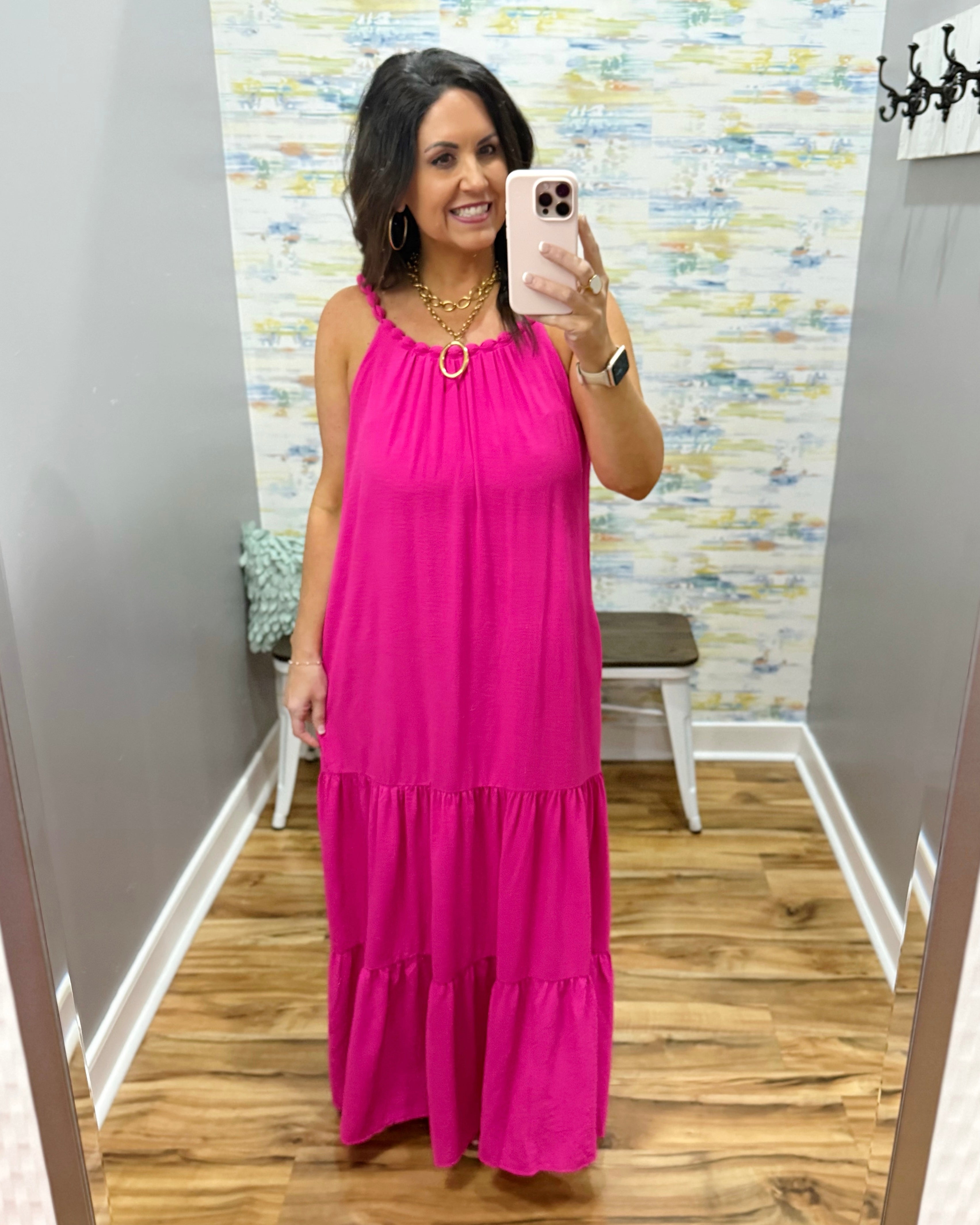 Woman wearing a pink dress in a room with a patterned wall.