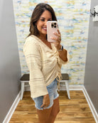 woman wearing a bell sleeve top in natural. 