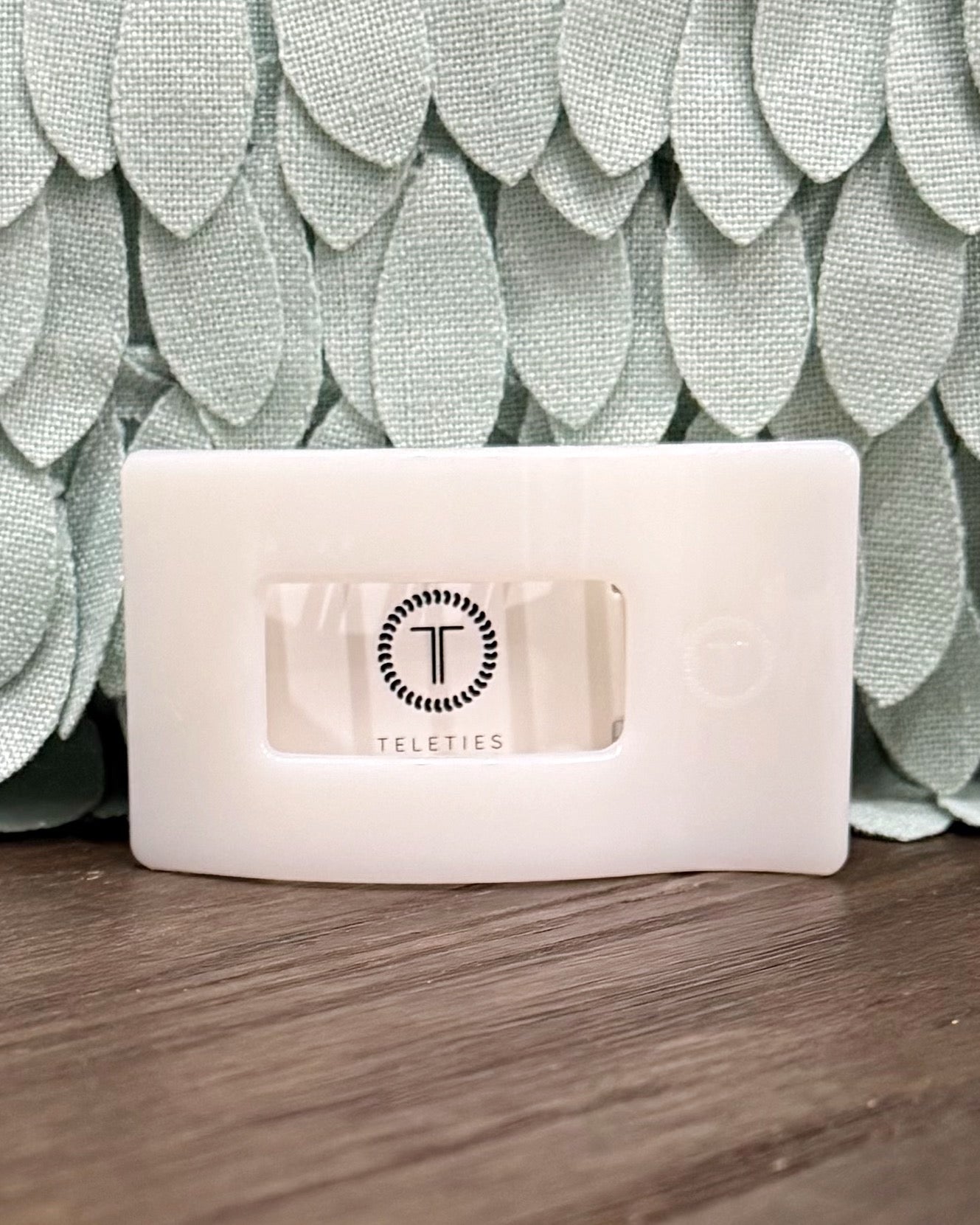 Rectangular product with 'Teleties' branding on a textured green background