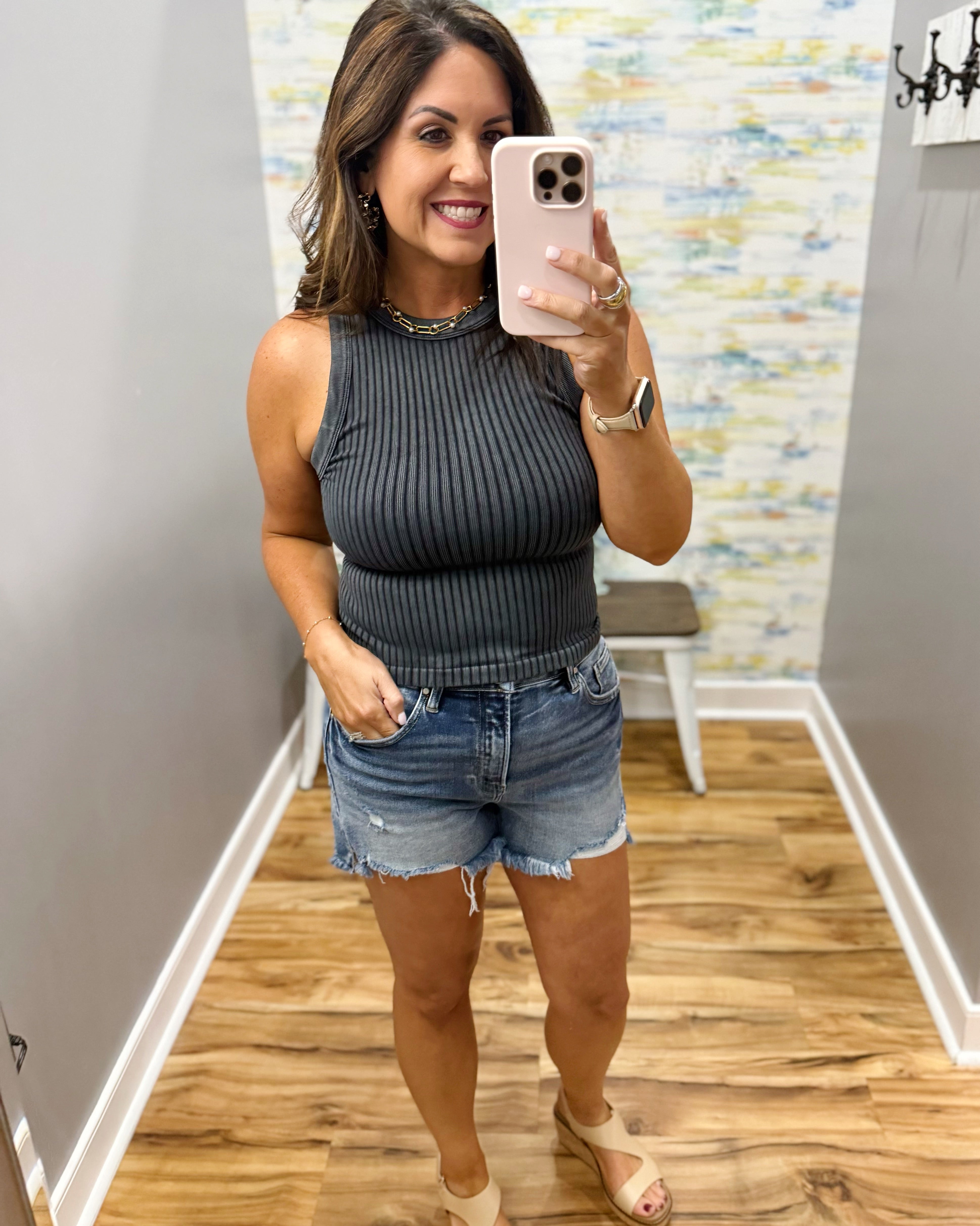 woman wearing black tank with denim shorts.