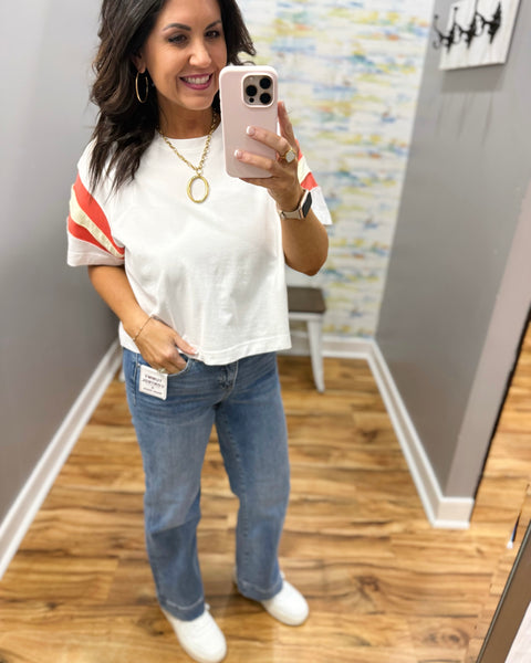 woman wearing white tee with colorful sleeves and chunky gold necklace