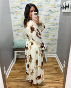 woman wearing a cream maxi dress with brown, black and taupe floral pattern. 