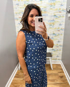 Woman taking a mirror selfie wearing a navy blue dress with white polka dots.