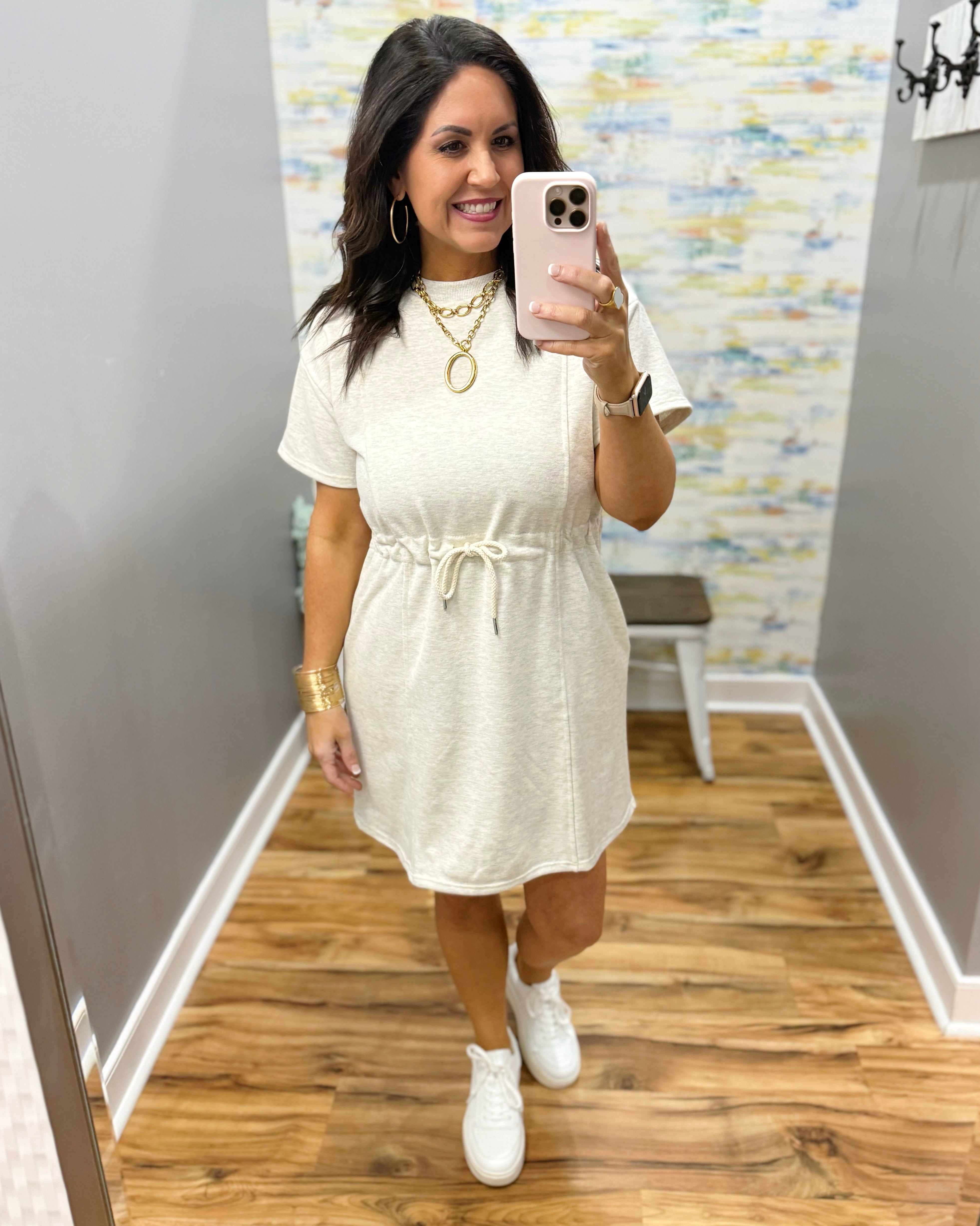 Woman wearing a neutral dress and white sneakers.