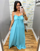 Woman taking a mirror selfie wearing a light blue dress in a room with a patterned wall.